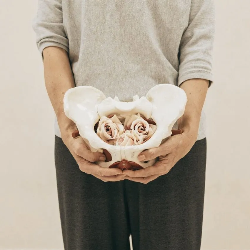 a woman holding a hip skeleton with roses in it